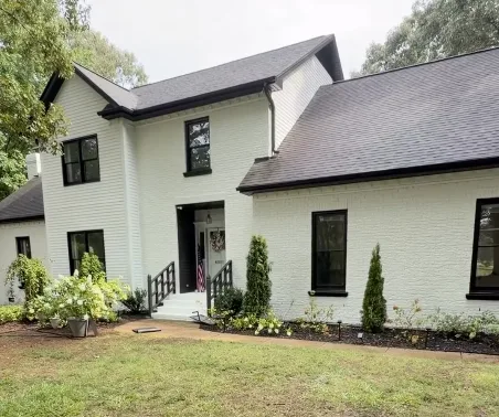 The same home with its brick painted crisp white and the trim and windows in black