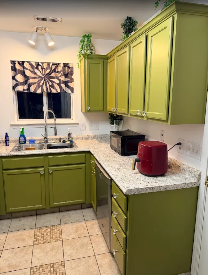 Kitchen cabinets finished in olive green with brushed hardware and light stone countertops by Brushworks Painting